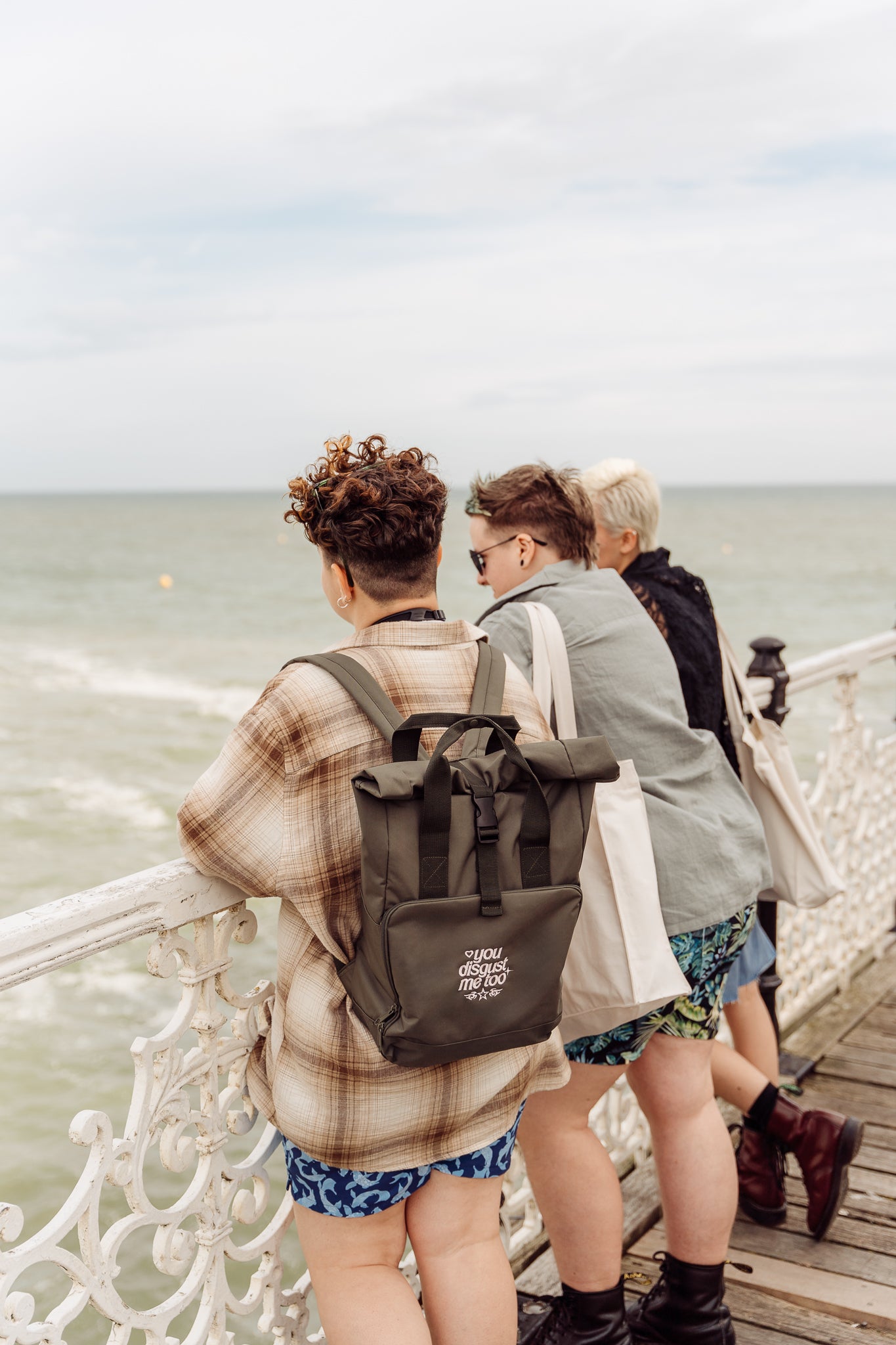 Three people standing on a pier looking out at the ocean.