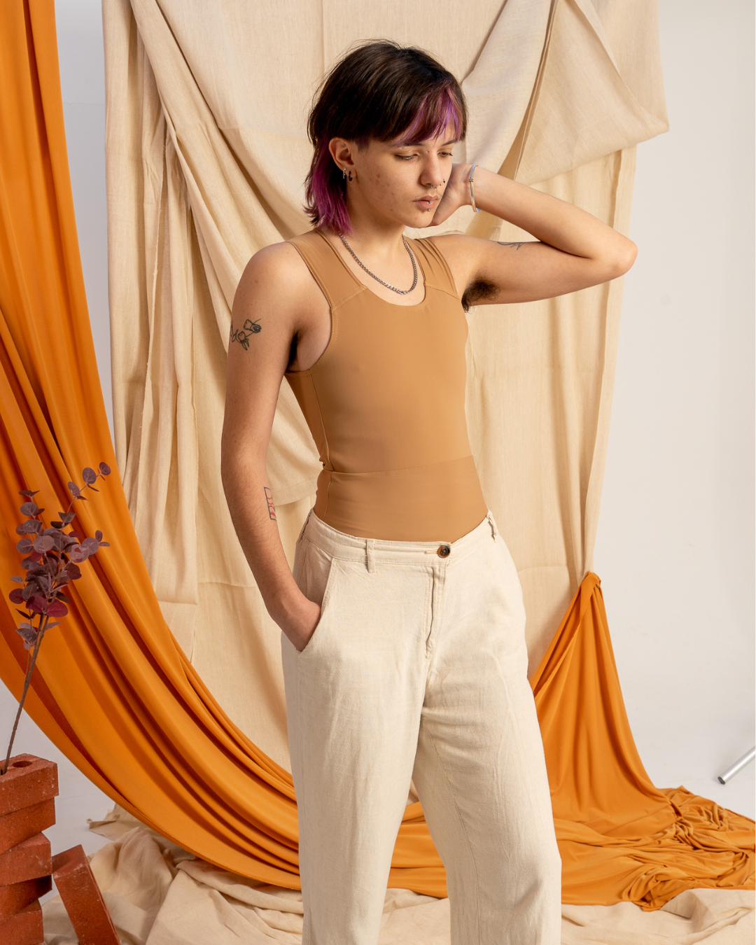 A person wearing a medium skin tone long chest binder with cream trousers.