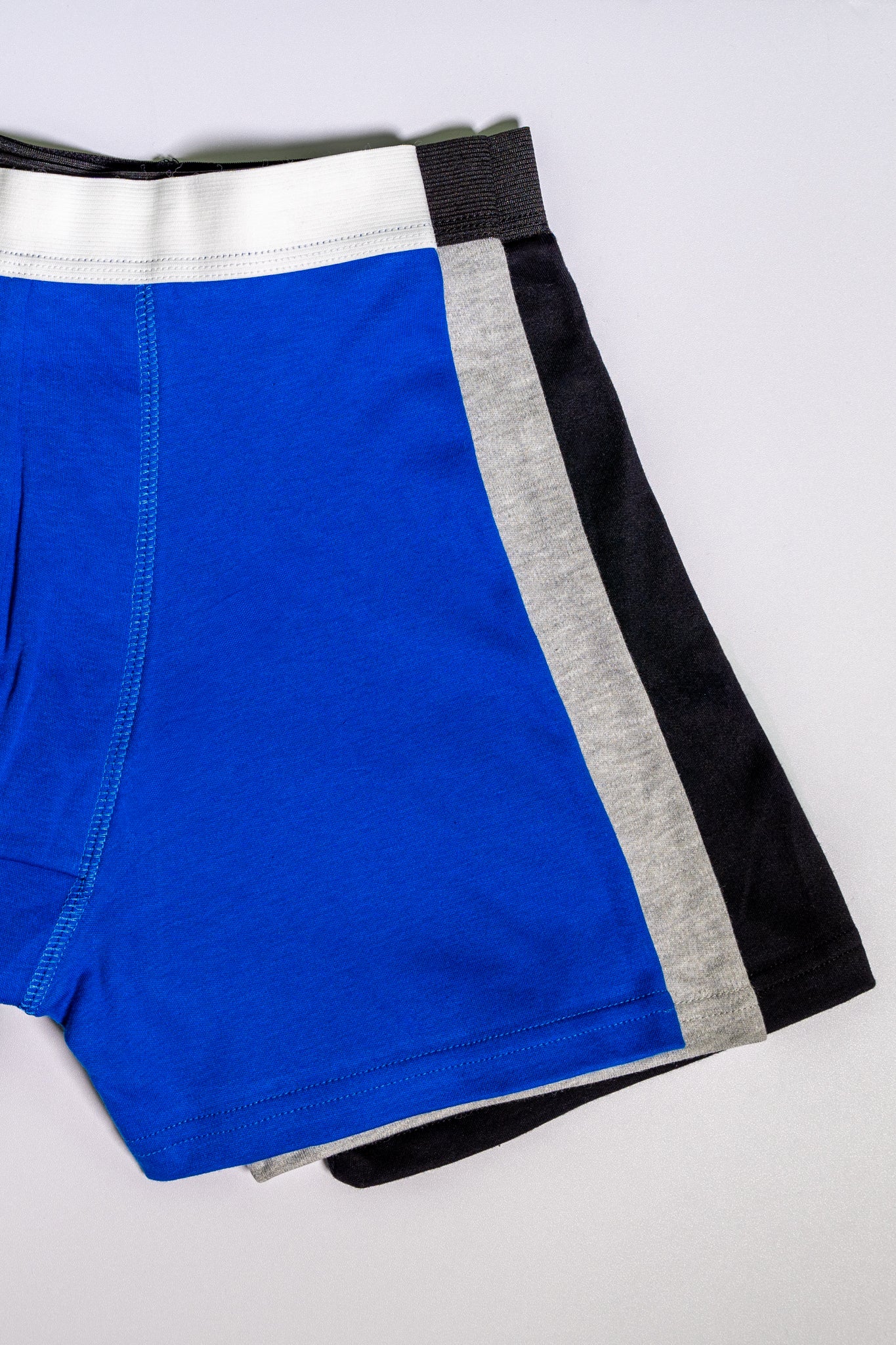 Blue boxers with black and gray side panels on a light gray background