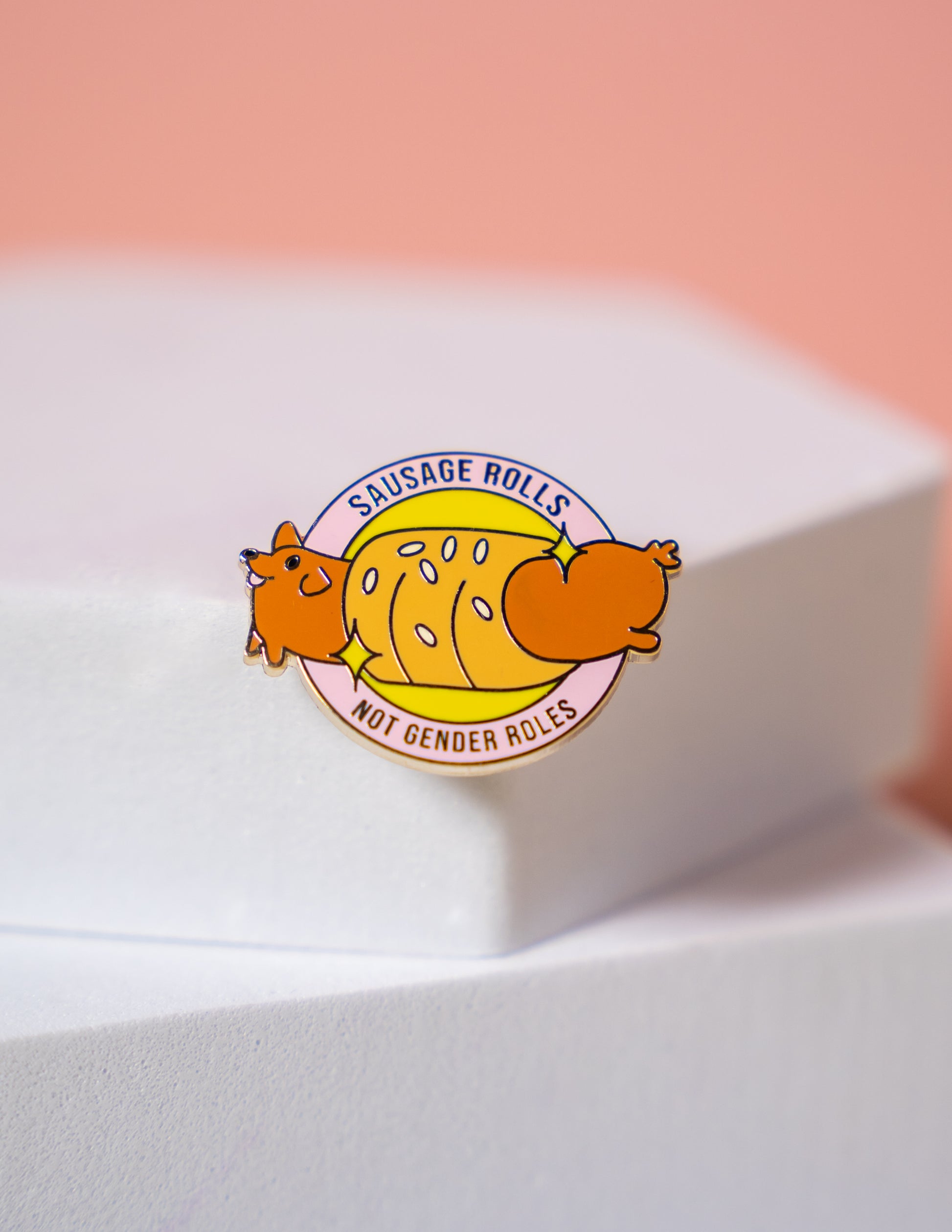 a small pin with a sausage dog inside a sausage roll reading "sausage rolls not gender roles" 