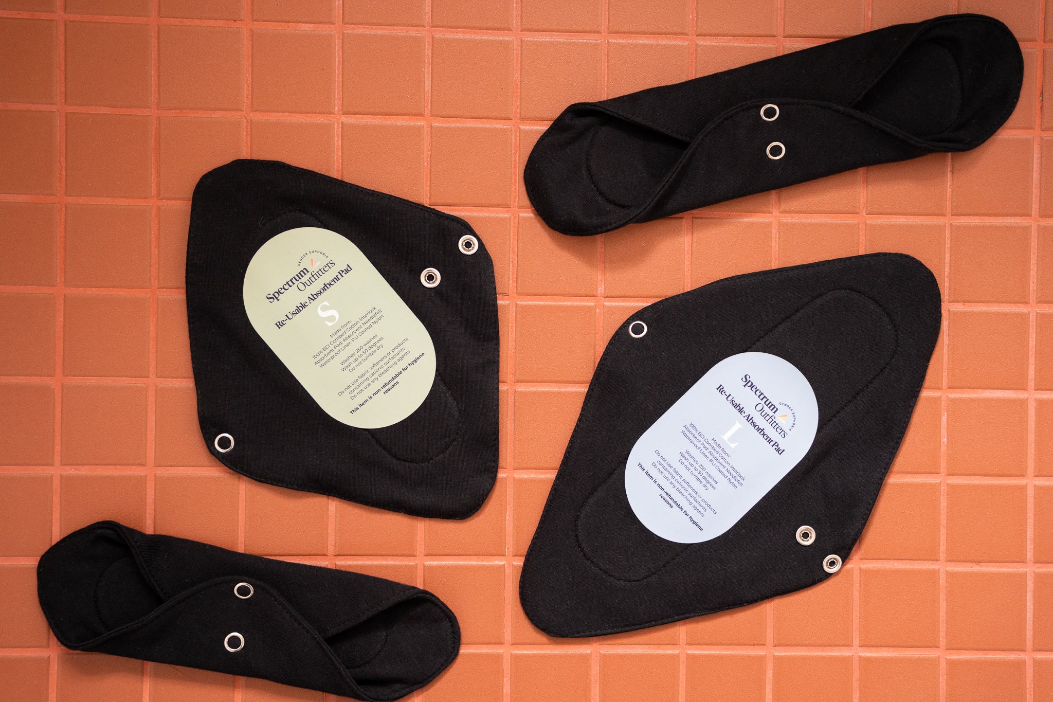 Black reusable sanitary pads with labels on a grid-patterned surface
